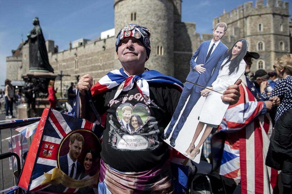 Một người hâm mộ gia đình hoàng gia trưng những vật kỷ niệm để chụp ảnh bên ngoài lâu đài Windsor. Ảnh: EPA-EFE.