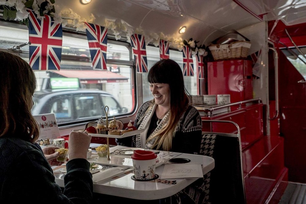 Hành khách trong chuyến thăm quan bằng xe buýt  ở London, trên xe được trang trí cờ hoa rực rỡ. Ảnh: NYT.
