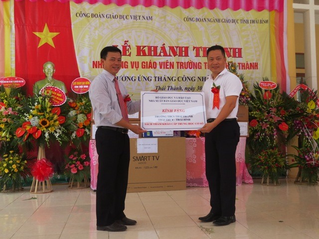 Ông Nguyễn Quốc Hồng - Phó Giám đốc, Chủ tịch CĐ Nhà Xuất bản Giáo dục VN (bên phải) tặng quà của Nhà Xuất bản Giáo dục VN cho Trường THCS Thái Thành. Ảnh: Xuân Trường