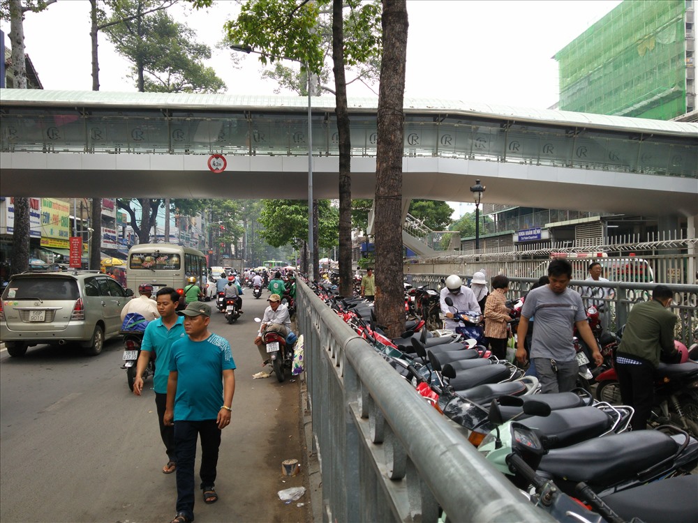 Phần bên trong hàng rào sắt trên vỉa hè bị chiếm dụng làm bãi giữ xe, người đi bộ phải đi dưới lòng đường Nguyễn Chí Thanh, Q.5