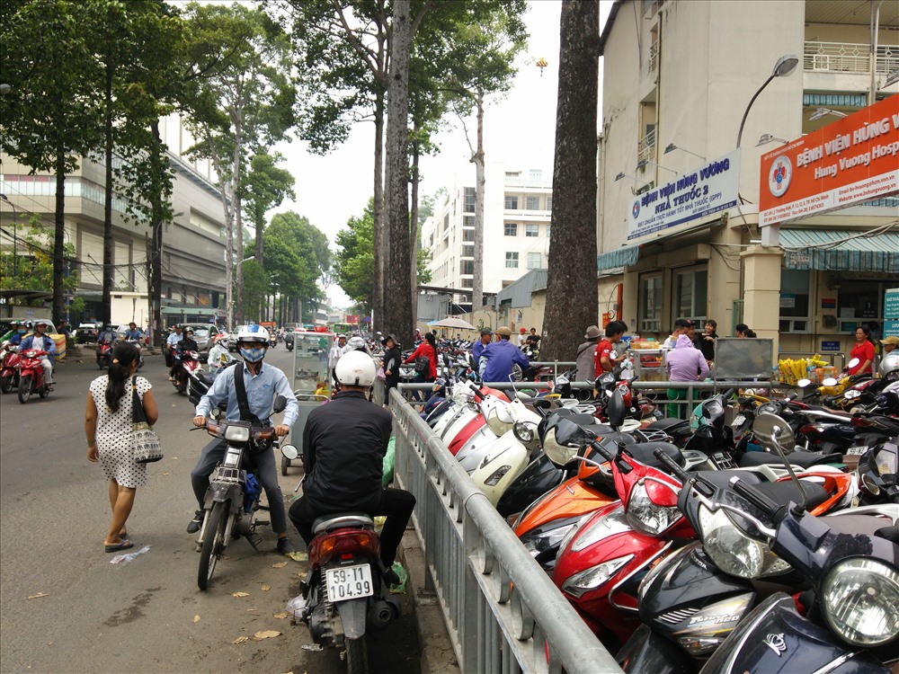 Vỉa hè trước bệnh viện Hùng Vương, Q.5 cũng bị chiếm trọn làm bãi giữ xe, người đi bộ đi dưới lòng đường.