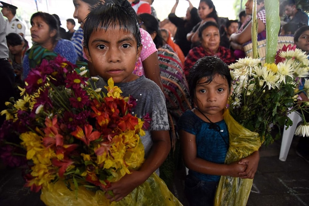  Những đứa trẻ cầm hoa trong đám tang của Erick Rivas, 20 tuổi, một nạn nhân của vụ phun trào núi lửa Fuego.