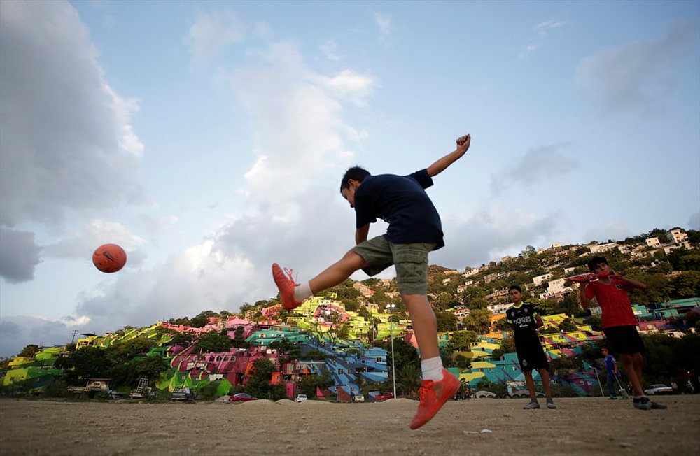 Một cậu bé đá một quả bóng trước những ngôi nhà nhiều màu trên sườn đồi ở Cerro de la Campana. Ảnh: Daniel Becerril / Reuters