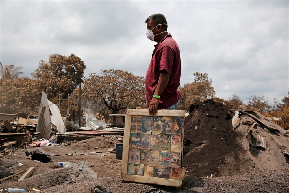 Người đàn ông giữ khung ảnh của gia đình sau trận phun trào của núi lửa Fuego. Ảnh: Reuters.