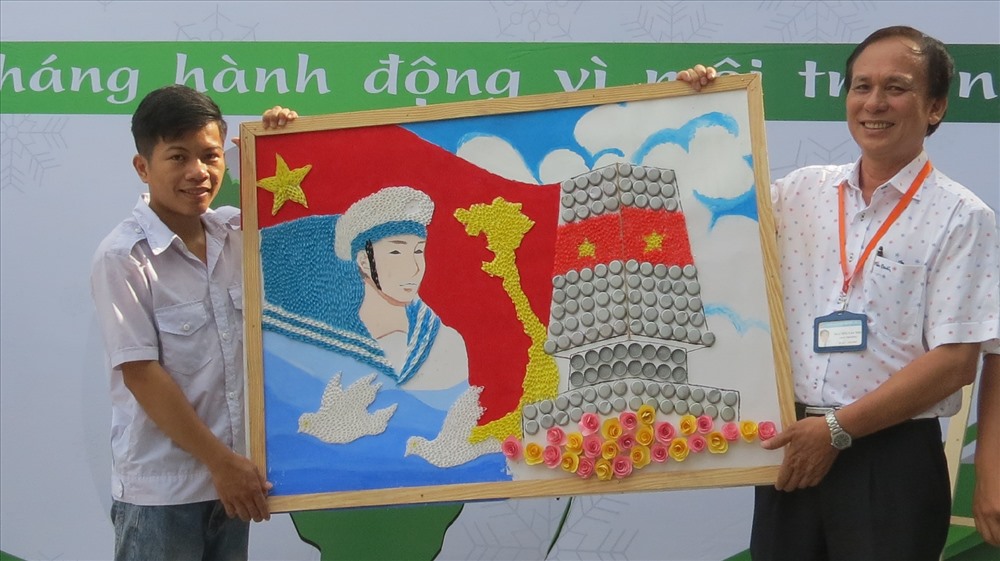 Thầy Nguyễn Văn Thu (phải ảnh) nhận bức tranh làm từ vật liệu tái chế từ Viện nghiên cứu Môi trường và Giao thông của trường - Ảnh: L.T