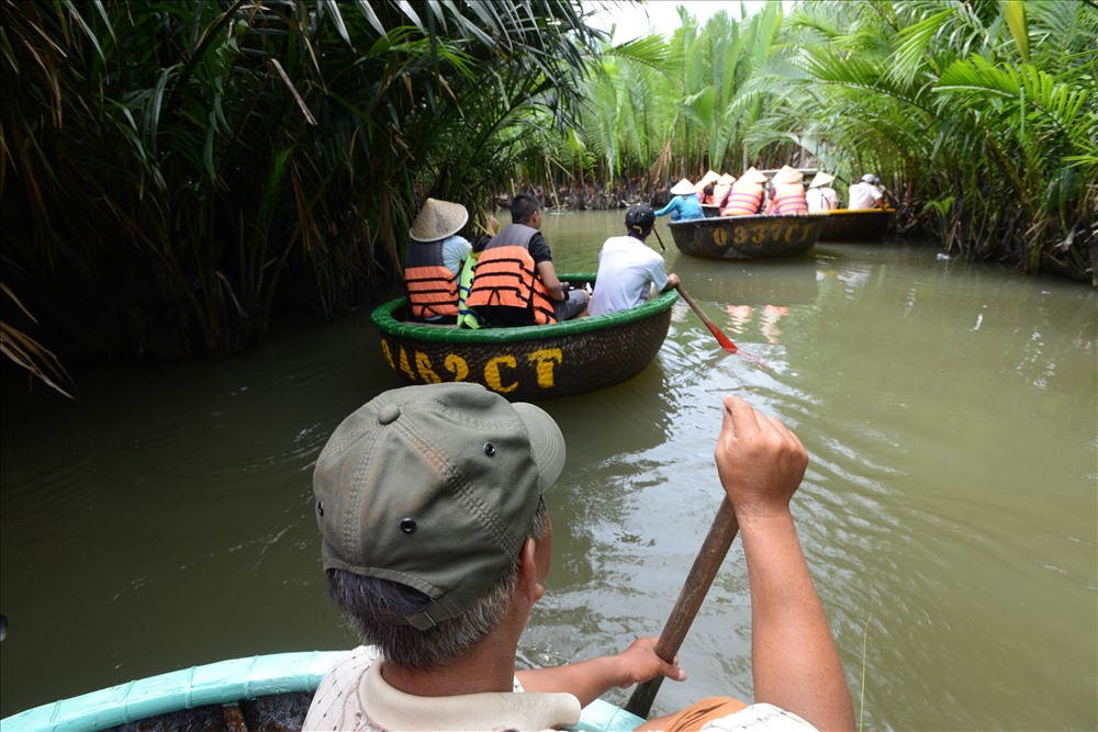 Du khách đi thuyền thúng len lỏi dạo chơi trong khu rừng dừa nước mát rượi. 