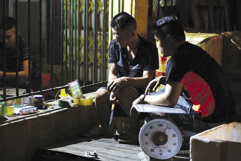 Người lao động xem World Cup qua điện thoại smartphone tại chợ Long Biên (Hà Nội). Ảnh: NAM NGUYỄN