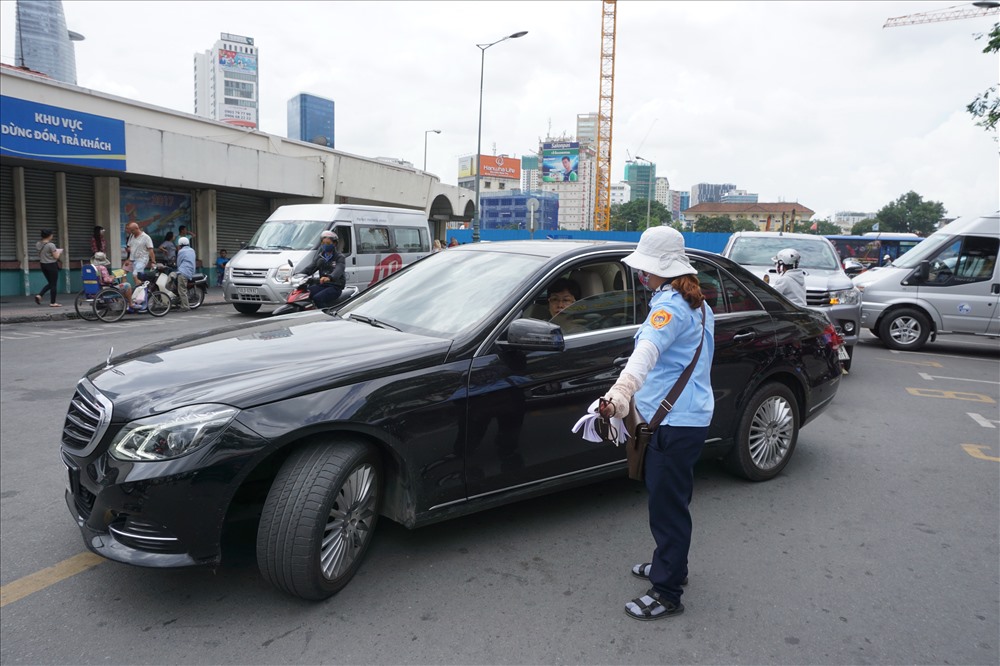 Nhân viên thu phí hướng dẫn cho xe ôtô vào đậu tại điểm đỗ xe ôtô có thu phí trên đường Phan Bội Châu (Q.1, TPHCM). Ảnh: MINH QUÂN
