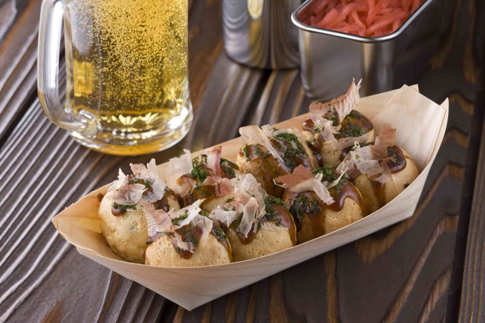 Takoyaki là một món ăn nhẹ nổi tiếng của Nhật Bản và thường được thưởng thức trong dịp lễ Obon. Takoyaki được làm từ bột bánh kếp, vo thành viên tròn và có nhân là bạc tuộc chiên. Khi ăn, người ta thường chan nước sốt okonomiyaki, katsuobushi (vảy cá ngừ khô) và aonori (rong biển xanh khô) lên bánh, tạo nên hương vị tuyệt vời. (Ảnh: Japan Times)