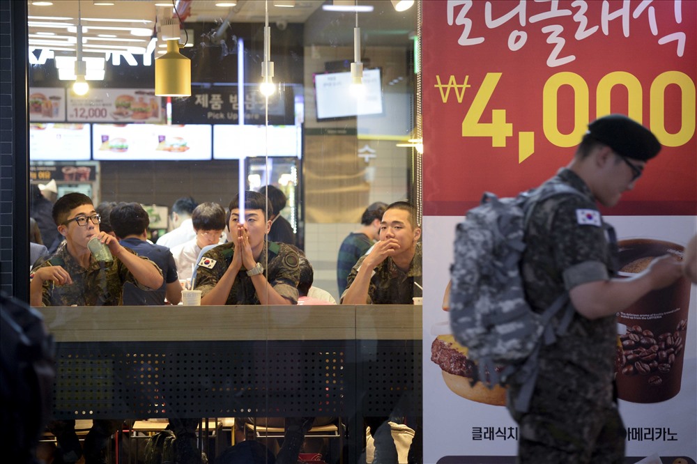 Binh sĩ Hàn Quốc tại một cửa hàng bán đồ ăn nhanh. Về lý thuyết, hai miền Triều Tiên vẫn đang trong tình trạng chiến tranh. Tất cả nam giới Hàn Quốc trong độ tuổi từ 18 - 35 đều phải thực hiện nghĩa vụ quân sự trong thời hạn 21 - 24 tháng. Phía bên kia vĩ tuyến 38, chính sách nghĩa vụ quân sự của Bắc Hàn thậm chí còn khắc nghiệt hơn.Từ tháng 1.2015, luật nghĩa vụ quân sự sửa đổi của Bắc Hàn quy định thời gian tại ngũ của nam giới cũng tăng từ 10 năm lên 11 năm, đối với phụ nữ là 7 năm. Binh sĩ chính quy hiện tại của Bắc Hàn là 1,1 triệu, dự bị khoảng 5,5 triệu người. Nếu riêng về con số, Bắc Hàn đứng thứ 4 trên thế giới về số lượng.