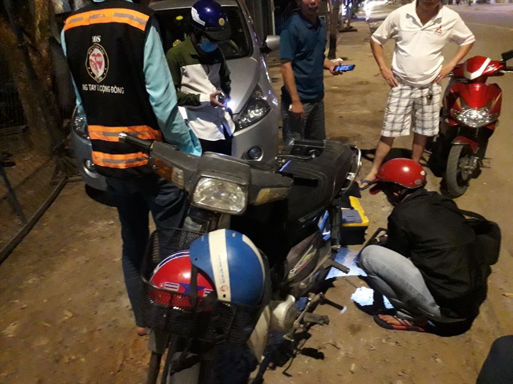 Thành viên Đội SOS vá xe cho người đi đường khi bị thủng xăm lúc đêm khuya.