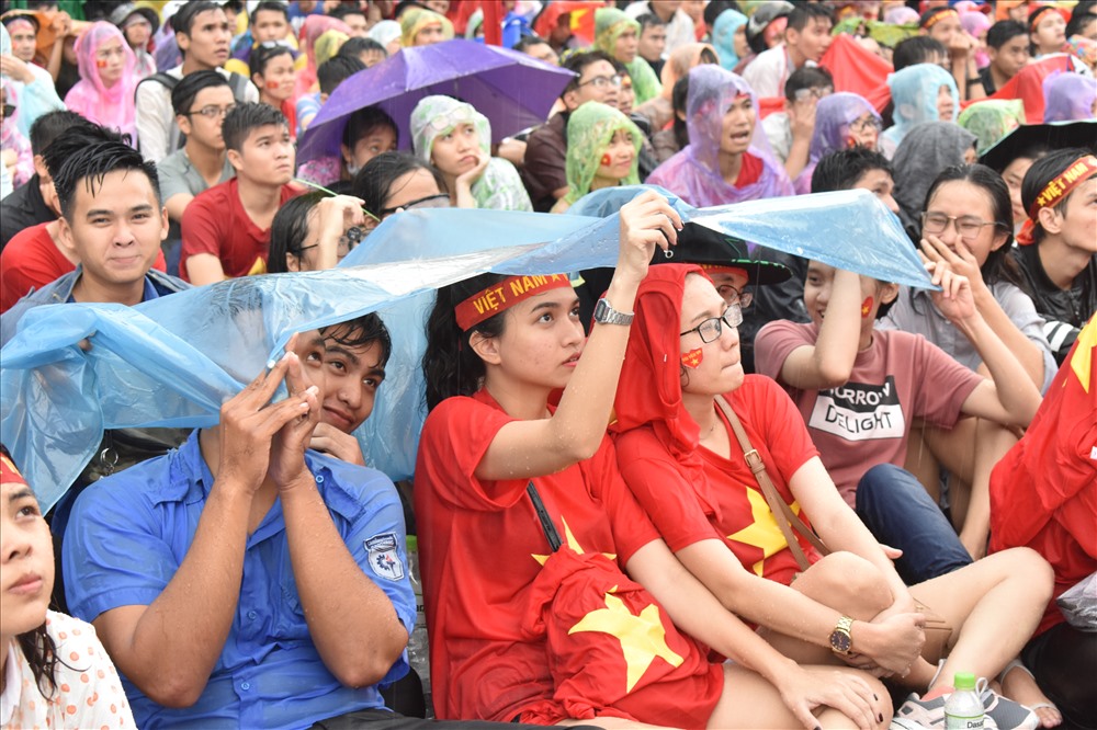 Mọi người chia sẻ áo mưa để cùng nhau xem bóng đá