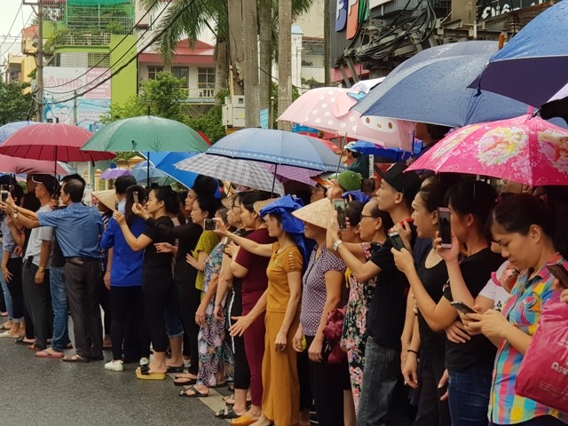 Người dân thành phố Ninh Bình đội mưa tập trung bên đường đón Đoàn xe đưa linh cữu Chủ tịch Nước Trần Đại Quang. Ảnh: NT