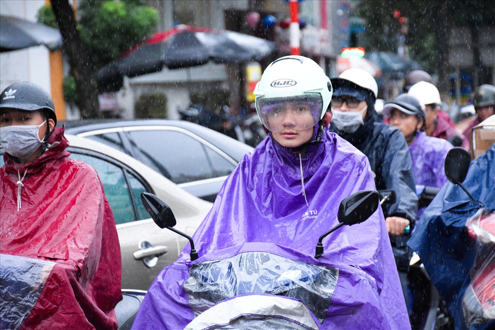 Nhiệt độ xuống thấp đột ngột kèm theo mưa rả rích khiến người dân phải mặc áo mưa khi ra đường.