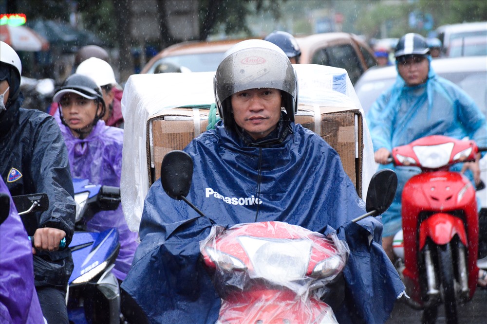 Nhiệt độ xuống thấp đột ngột kèm theo mưa rả rích khiến người dân phải mặc áo mưa khi ra đường.