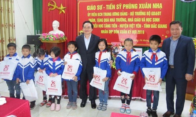 Bộ trưởng Phùng Xuân Nhạ tặng quà cho học sinh Trường Tiểu học Tăng Tiến. Ảnh: Xuân Trường