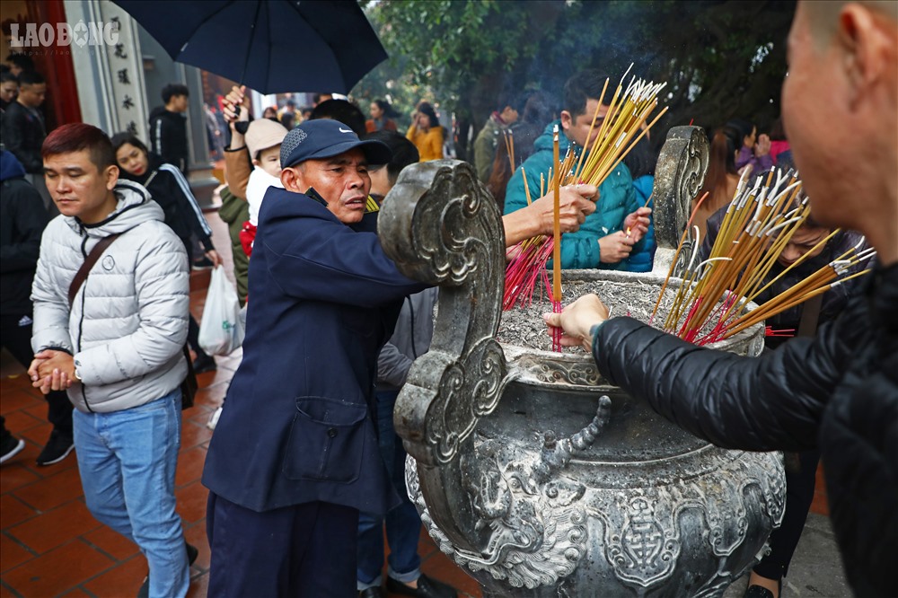 Lực lượng bảo vệ thu dọn bớt hương mà người dân cắm bên ngoài nhà đền.