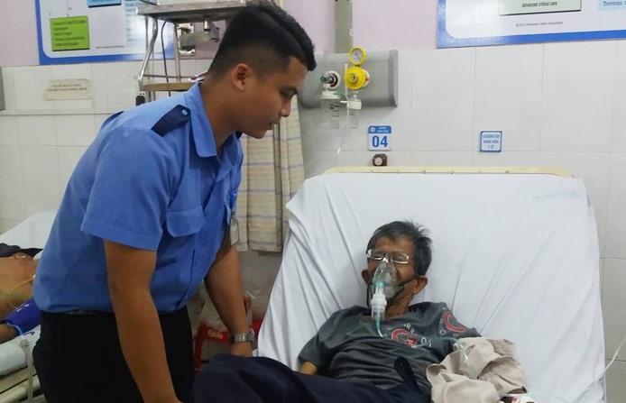 Bảo vệ Nguyễn Minh Tâm bên cạnh người bệnh được anh cõng đi cấp cứu