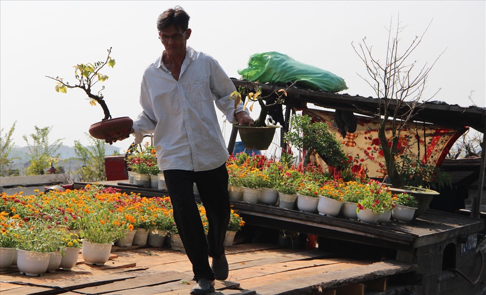 Lão nông Mai Hữu Thành đưa hoa từ dưới thuyền lên bến.