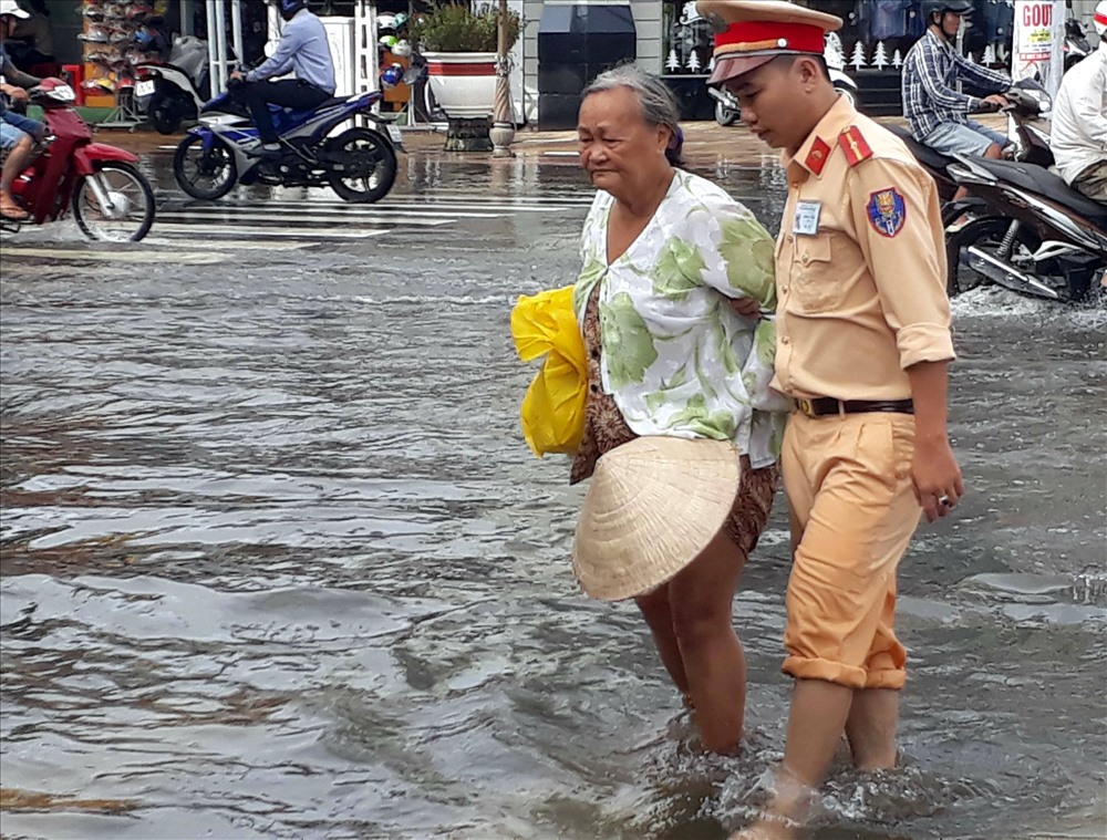 CSGT giúp người già qua đường đoạn ngập nước do ảnh hưởng bão số 1 (ảnh Nhật Hồ)