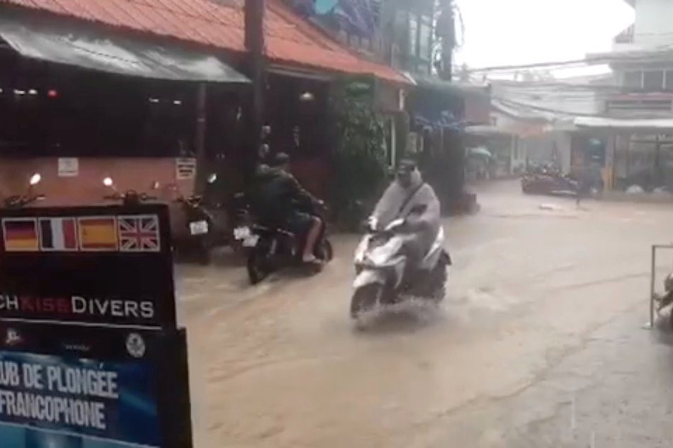 Người đi xe máy đi dọc theo một con đường bị ngập lụt khi cơn bão nhiệt đới xuất hiện trên đảo Koh Tao, Thái Lan, thứ bảy 