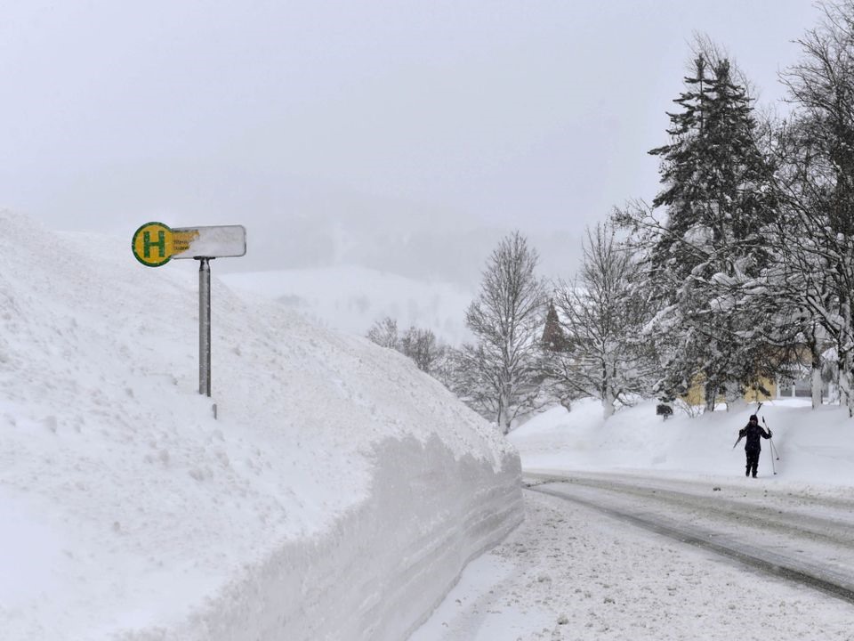 Một người trượt tuyết đi bộ qua trạm xe buýt sau khi tuyết rơi dày đặc ở ngôi làng tại Filzmoos, Áo. Ảnh: Sky. 