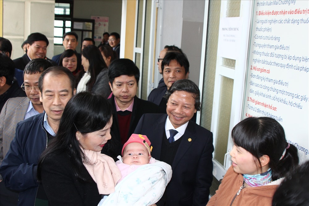 Bộ trưởng Tiến hướng dẫn cho các bà mẹ về cách chăm sóc trẻ sau khi tiêm phòng vắc xin. Ảnh: Thùy Linh