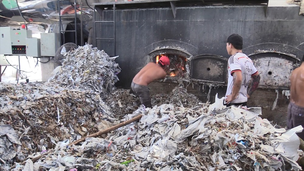 Công nhân đổ rác thải công nghiệp vào lò đốt của công ty sản xuất giấy.