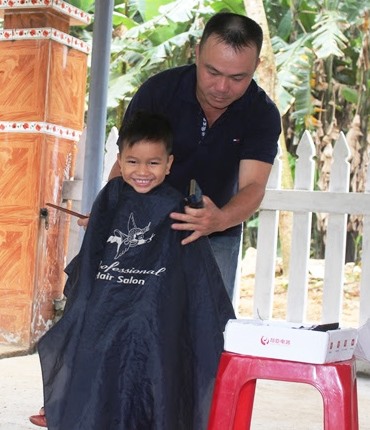 Anh Trà lang thang khắp các thôn bản chỉ để cắt tóc cho trẻ em, thanh niên và người già. Ảnh: Đ.V