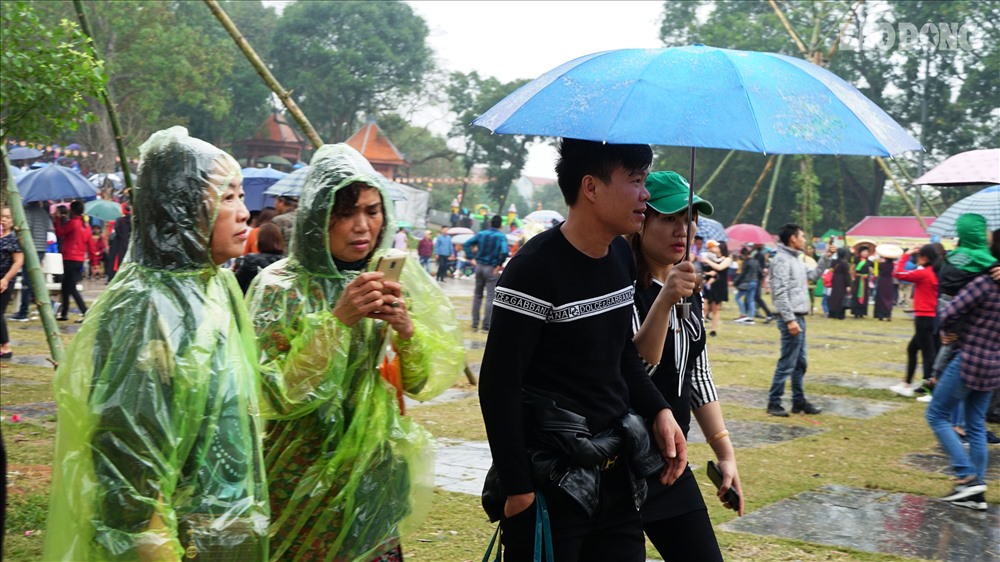 Người dân mặc áo mưa, che ô lần lượt đi vào bên trong trung tâm hội.