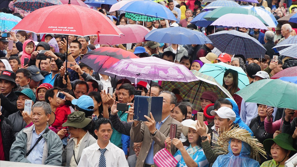 Nhiều người mặc áo mưa, che ô tiến về phía sân khấu trung tâm Hội Lim.