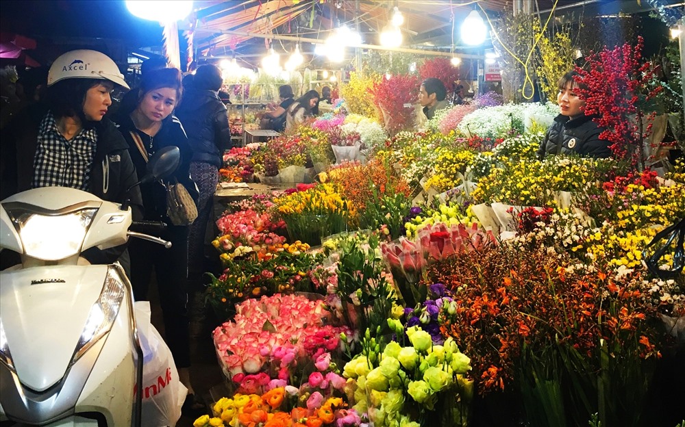 Người dân đi chợ đêm tận hưởng không khí xuân về và mua cho mình như bó hoa tươi thắm.