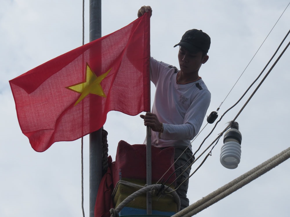 Người dân Hải Tân treo cờ Tổ quốc mới.  Ảnh: H.N