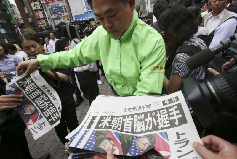 Tại ga Shimbashi ở Tokyo, nhân viên của một tờ báo Nhật Bản Yomiuri phát ấn bản bổ sung của tờ báo về cuộc gặp thượng đỉnh giữa Tổng thống Donald Trump và nhà lãnh đạo Kim Jong Un tại Singapore. Ảnh: AP. 