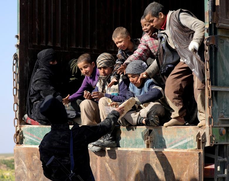 Một người lính Syria tặng bánh mì cho trẻ em gần làng Baghouz (tỉnh Deir Al Zor, Syria). Ảnh: Reuters