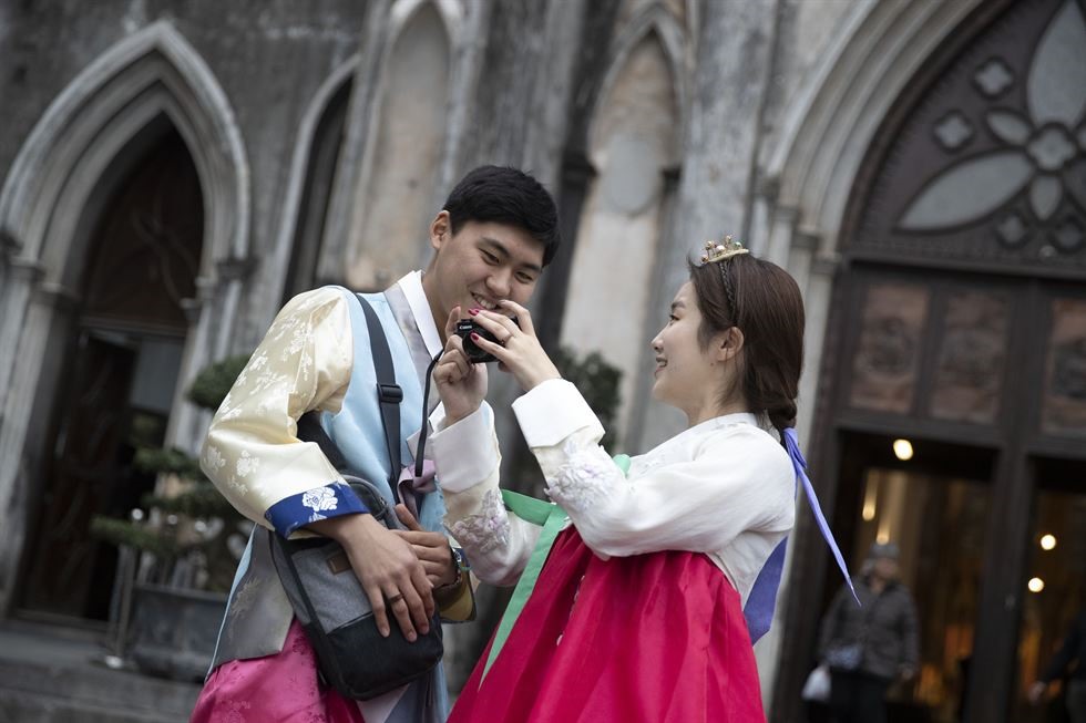 Lee Won-jae (trái) và Kim Seung-hee - cặp đôi người Hàn Quốc trong trang phục truyền thống của Hàn Quốc - hanbok chụp ảnh trước nhà thờ St.Joseph ở quận Hoàn Kiếm, Hà Nội hôm 24.2. Ảnh: Korea Times. 