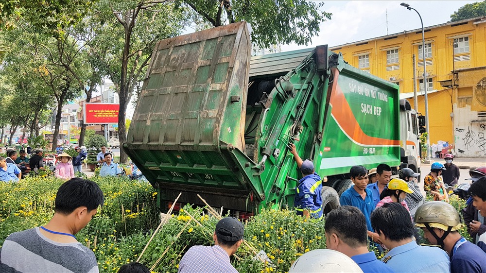 Đến gần 13h, hàng trăm chậu hoa của anh Sang bị vứt vào xe rác nhưng anh vẫn kiên quyết không cho, ai đưa 100 nghìn thì mang 1 cặp về, còn lại thì cho lên xe rác. Ảnh: Trường Sơn