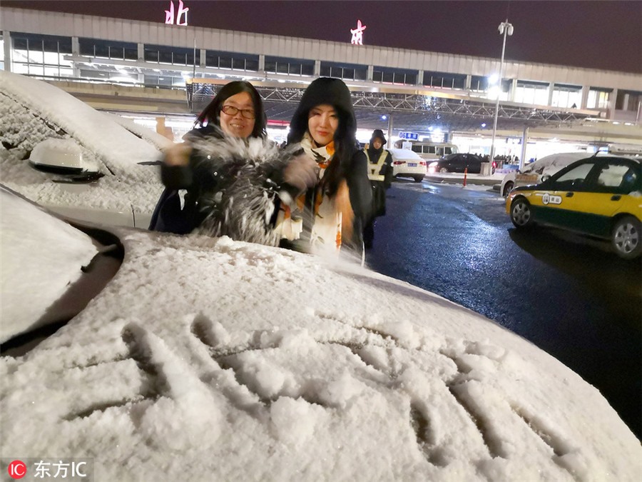 Một người mẹ và cô con gái tỏ ra phấn khích đón đợt tuyết đầu tiên tại Nhà ga số 3 của Sân bay Quốc tế Thủ đô Bắc Kinh.