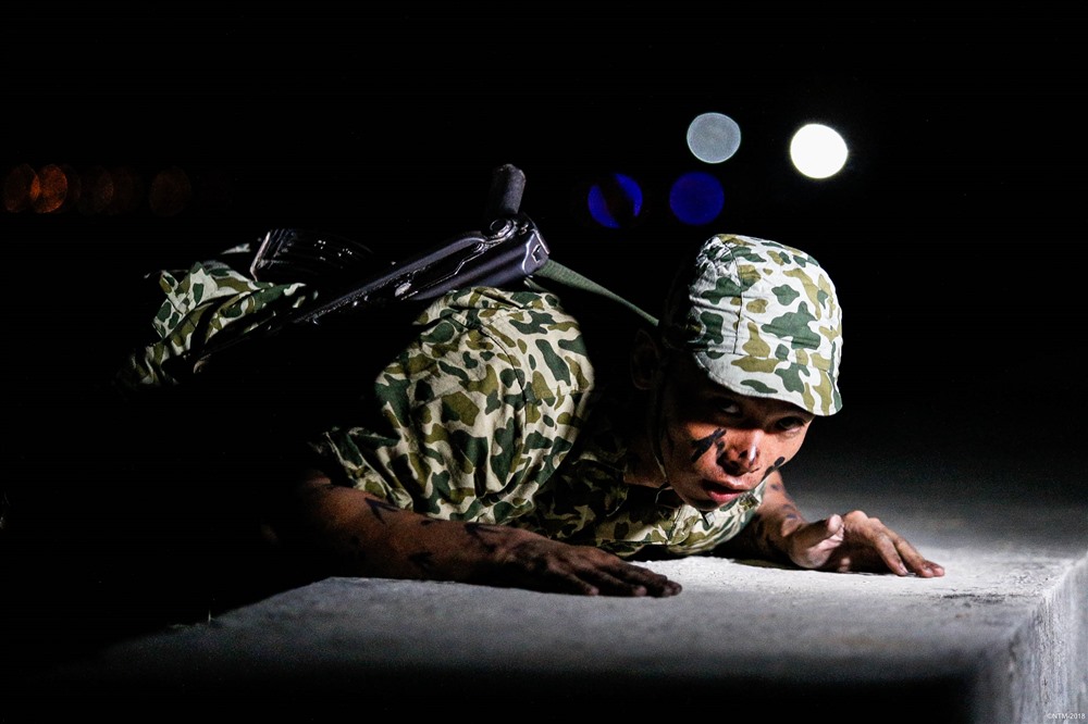 Một chiến sĩ đang luyện tập thao tác áp sát kè để tiếp cận lô cốt địch trong điều kiện thời gian ban đêm.