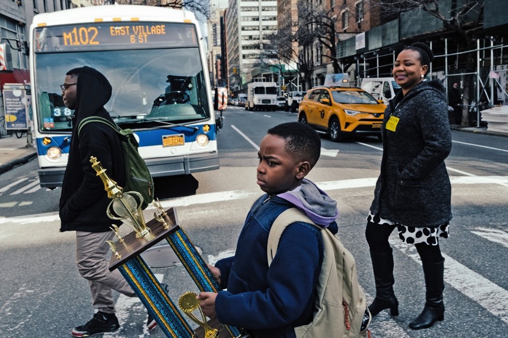 Tani mang về nhà chiếc cúp cờ của mình từ trường về nhà, cùng   theo mẹ và anh trai. Ảnh: The New York Times