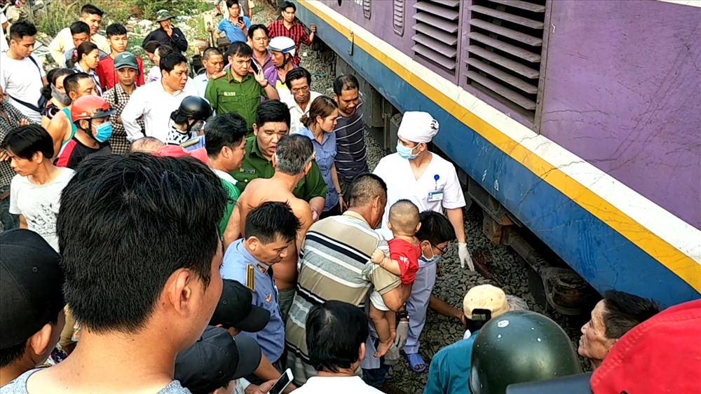 Lực lượng cứu hộ cùng rất nhiều người dân hỗ trợ đưa nạn nhân ra khỏi gầm tàu hỏa. Ảnh: T.S