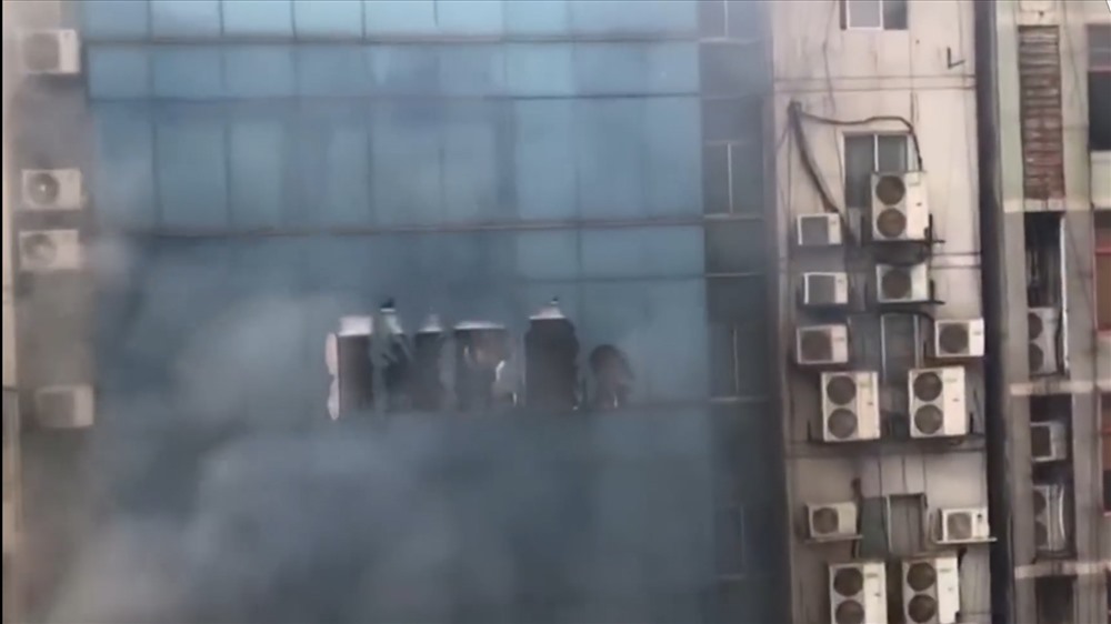 Nhiều người đứng ở các tầng 13 và 14 kêu cứu, trong khi lúc đó khói đen vẫn tiếp tục bao trùm tòa nhà.
