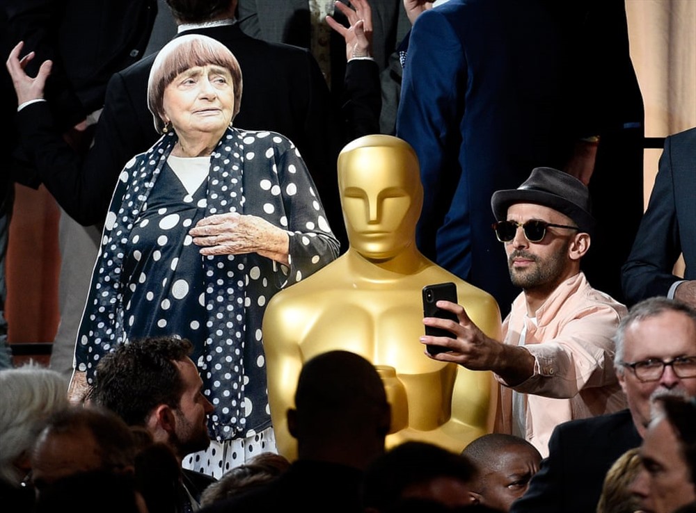 Nghệ sĩ /nhà làm phim JR (phải), đạo diễn phim Varda of Faces Place chụp ảnh tự sướng với một bức tượng Oscar và một tấm bìa cứng in hình Varda trong Lễ trao giải đề cử của Viện hàn lâm thường niên lần thứ 90, năm 2018. Ảnh Getty Images
