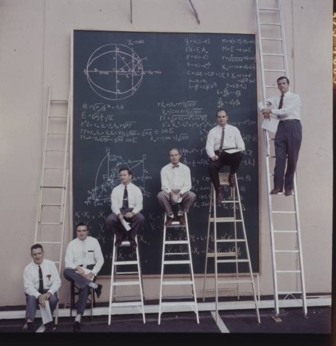 Các nhà khoa học NASA tạo dáng trước một tấm bảng đầy những phép tính phức tạp.  