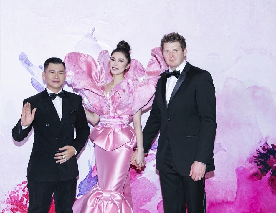 Hoa hậu Hoàn vũ cùng chồng (bên phải) vui vẻ hội ngộ bên nhà thiết kế Hoàng Minh Hà. Ảnh: NVCC. 