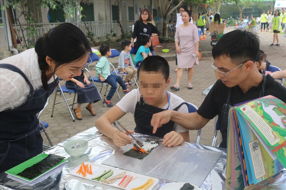Anh Trần Hương Khuê (ngoài cùng bên phải) chơi cùng con trai trong trò “Lá khéo léo”.