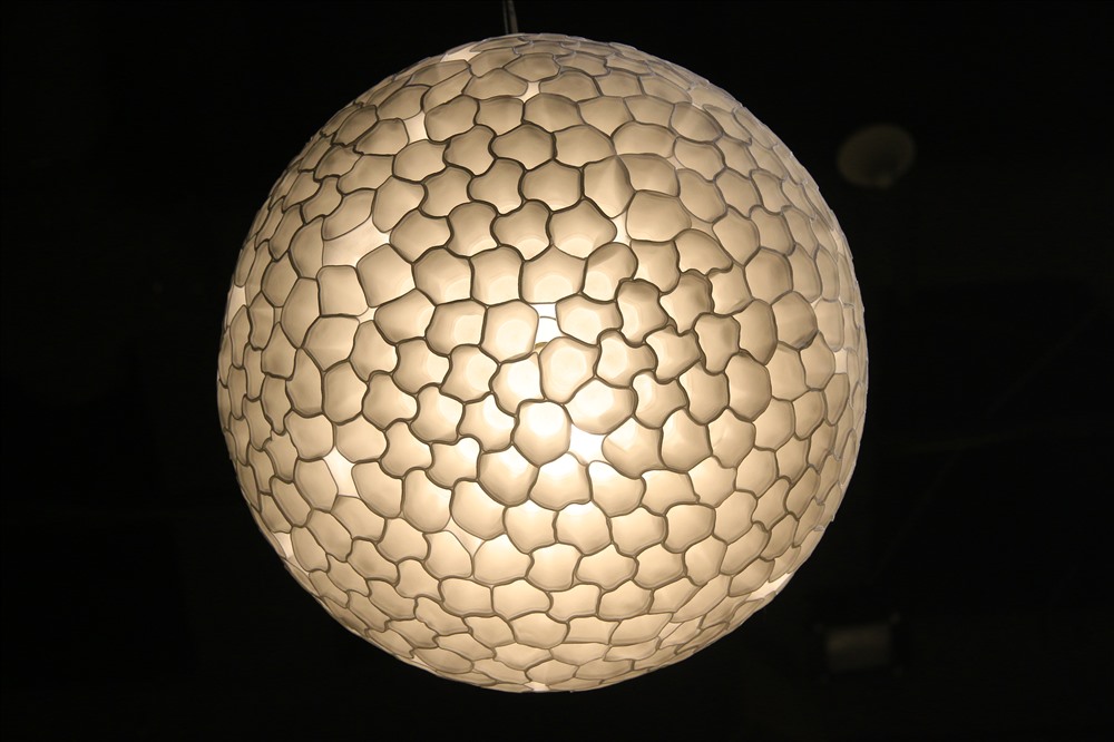 Một trong những đồ trưng bày gây ấn tượng với khách tới xem triển lãm là chiếc đèn được tạo ra từ hàng nghìn chiếc cốc nhỏ loại sử dụng một lần. Sau khi được xử lý ở nhiệt độ cao, chúng co lại thành những hình thù đa dạng và được gắn với nhau. Đây là sản phẩm của Paul Cocksedge đến từ Anh.