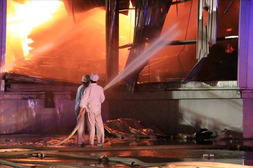 Hai công nhân mặc áo trắng của Cty cổ phần sữa Vinamilk ôm vòi nước trực tiếp tham gia dập lửa.