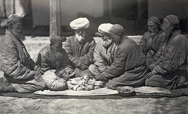 Cảnh một nhóm người đàn ông ngồi trên mặt đất gần một cậu bé đang được cắt bao quy đầu. Ảnh: Ancient-origins.