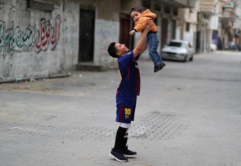 Nofal chơi với em trai của mình bên ngoài nhà của em ở trung tâm Dải Gaza